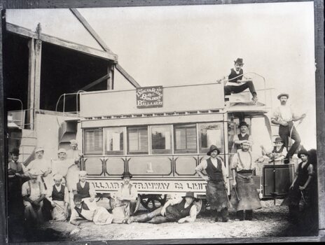 A group of men stand around and on a two-story or double deck tram car with "Ballaarat" and "Tramway Co Ltd" visible on its side.