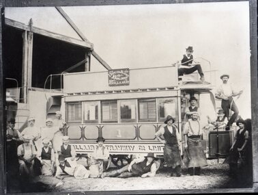 A group of men stand around and on a two-story or double deck tram car with "Ballaarat" and "Tramway Co Ltd" visible on its side.