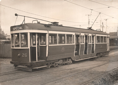 A vintage tram car numbered 26, with "SPECIAL" written on its front, stands on tram tracks with open doors and numerous windows.
