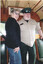 A woman and a man in a tram car, the man wearing a uniform cap and shirt with sunglasses perched on the cap.