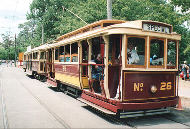 A vintage burgundy and yellow tram labeled "SPECIAL" and "№ 26" is parked on tram tracks with trees in the background.