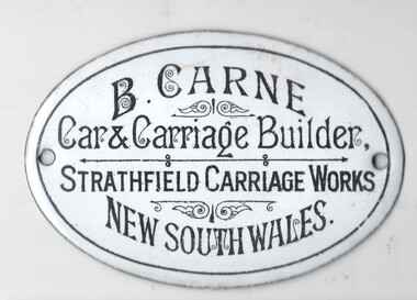 Oval enameled metal plaque with black text on a white background, reading "B. CARNE, Car & Carriage Builder, STRATHFIELD CARRIAGE WORKS, NEW SOUTH WALES."