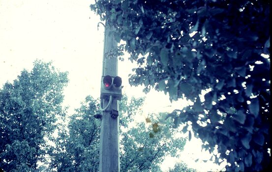 A wooden utility or power pole with a tramway signal light attached showing a red light.