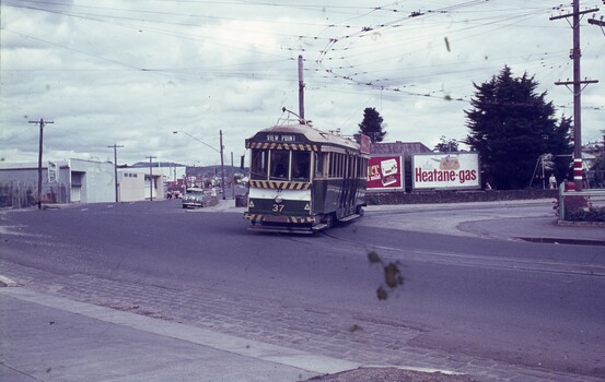 A green and cream tram numbered 37 with "VIEW POINT" displayed on its front travels on a road with overhead wires.