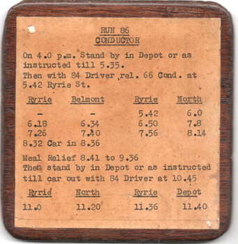 A wooden-framed schedule card titled "RUN 86 CONDUCTOR" with printed text detailing instructions and timetables for a conductor's route.
