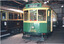 Two vintage trams, one green with destination sign "DEPOT" and number 466, parked inside a depot building.
