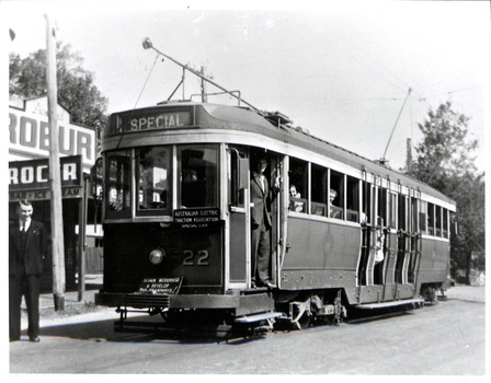 A vintage electric tram, numbered 22 and labeled "SPECIAL," stands at a stop with passengers visible through its windows.