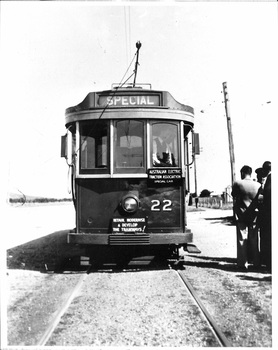 Front view of a vintage tram numbered 22 with "SPECIAL" displayed above the windshield, standing on tram tracks with a few people visible on the right side.