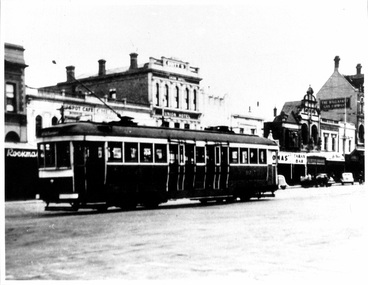 A vintage tram travels down a street lined with historic buildings.
