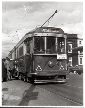 Tramcar, number 41, with "Gardens" destination sign, stopped on a street, with passengers boarding on the left and buildings in the background.