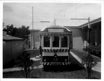 Front view of the "Zion Kindertram" No. 42, a vintage tram with striped bumper, parked on a paved path in front of a building.