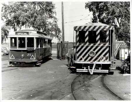 Two vintage electric trams on tracks, one with a "SPECIAL" sign and number 21, the other with diagonal stripes.