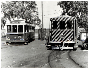 Two vintage electric trams on tracks, one with a "SPECIAL" sign and number 21, the other with diagonal stripes.