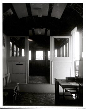 Interior view of an old-fashioned tram car, showing rows of windows and doors leading to other compartments.