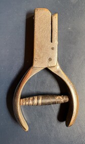 A close-up overhead view of a vintage metal hole or ticket puncher