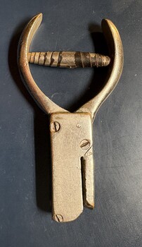 A close-up overhead view of a vintage metal hole or ticket puncher