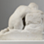 Marble sculpture of naked female slumped onto her knees, with lowered head viewed from the back. She sits on a rectangular base