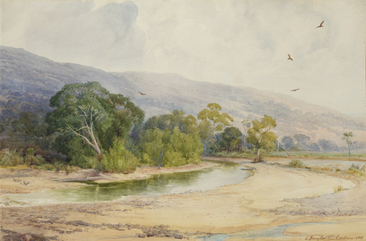 Landscape of a sandy bank with a river winding through the foreground, trees along the river. Blue faded mountains in the background. Cloudy sky with four birds flying above.