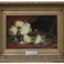 Still life painting of cream or yellow roses on a table partially obscuring a violin or fiddle sit on a red patterned table cloth. Red and brown background.  Housed in a thick decorative gold frame with plaque attached.