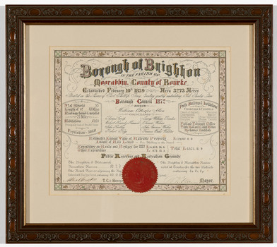 Framed certificate in mainly black, red and gold ink on cream paper, with decorative floral border. Gives details of the municipality and has a red wax seal at bottom of certificate. Has a cream mount and carved timber frame.