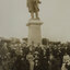 A group of seated and standing men and women in front of the large bronze statue of Sir Thomas Bent, which sits on a tall granite pedestal.