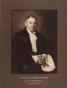 Sepia photograph of formal portrait of seated man with short grey hair wearing mayoral robes with fur trims and lace cuffs and jabot.