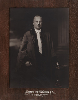 Sepia photograph of a formal portrait of standing man with short grey hair wearing mayoral robes with fur trims, white shirt, waistcoat underneath and jabot