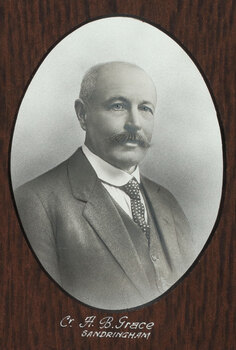Black and white photograph of an oval portrait of a suited man with balding grey hair and moustache