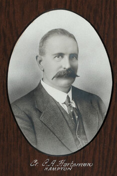 Black and white photograph of an oval portrait of a suited man with balding hair and moustache