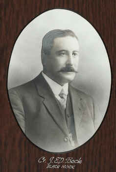 Black and white photograph of an oval portrait of a suited man with darkhair and moustache