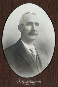 Black and white photograph of an oval portrait of a suited man with balding white hair and dark moustache