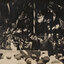 Sepia photograph of a man in a top hat upon a stage in front of a large crowd of people