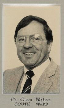 Black and white photograph of a photographic portrait of a man with dark hair and glasses in a suit and tie.