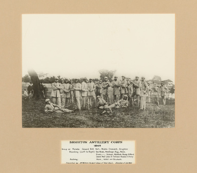 A black and white photograph of a group of men in 19th century military uniform standing and laying on the ground posing for portrait with rifles