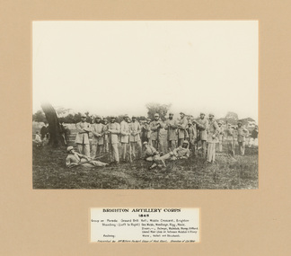 A black and white photograph of a group of men in 19th century military uniform standing and laying on the ground posing for portrait with rifles