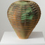 Vase with wavy pattern in bronze and green tones on a white plinth