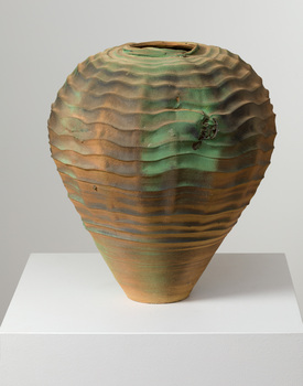 Vase with wavy pattern in bronze and green tones on a white plinth