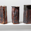 Three bronze and orange coloured rectangle shaped vases on a white ledge