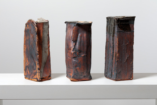 Three bronze and orange coloured rectangle shaped vases on a white ledge