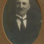 Black and white photograph of a man in a dark suit and patterned tie