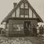 Black and white photograph of 2 men standing in the doorway of a small building