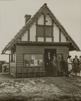 Black and white photograph of 2 men standing in the doorway of a small building