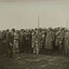 Black and white photograph of a suited man hitting a golf ball in front of a crowd