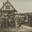Black and white photograph of a crowd gathering around officials outside of a small building