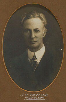 Black and white photograph of a man with grey hair in a dark suit and tie