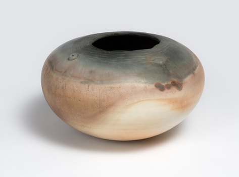 A round earthenware vase in pink and grey tones.