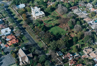Aerial photograph featuring a large double story white mansion with expansive gardens surrounding. 