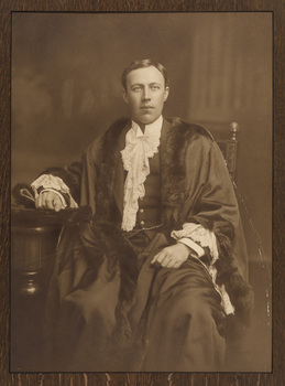 Black and white photograph of a formal portrait of a seated man wearing mayoral robes, fur trims and lace cuffs and jabot.