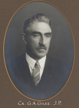 Black and white photograph of an oval portrait of a man in a suit with grey hair and a moustache