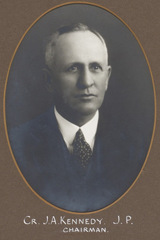 Black and white photograph of an oval portrait of a man in a suit with grey hair